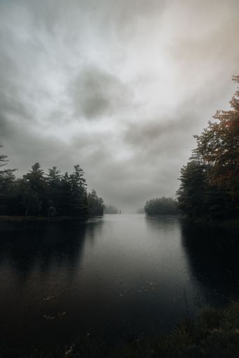 A beautiful vertical shot of a lake in Adirondack Mountains under the stormy sky