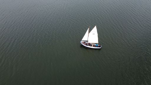 An aerial view of a schooner sailing in a tranquil sea