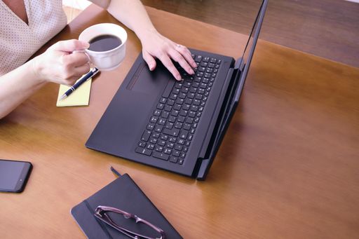 A high angle shot of a busy businesswoman using her laptop working at home while drinking coffee