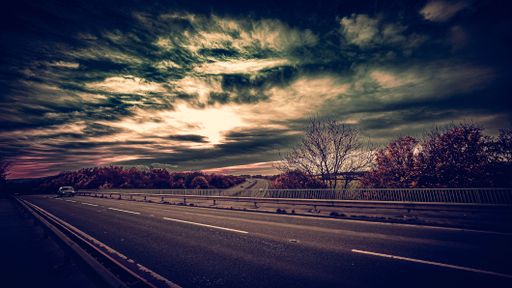 A highway with a car driving under a blue sky