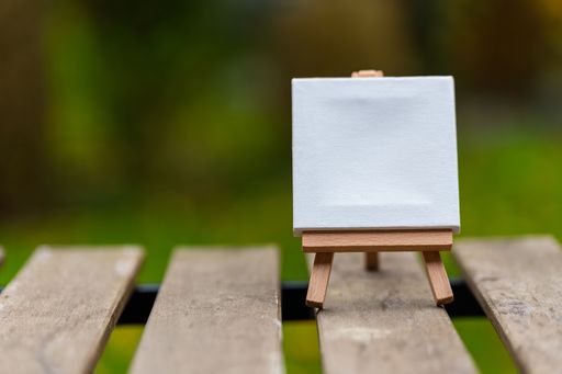 A closeup of a tiny canvas with space for text on a stand on a wooden surface