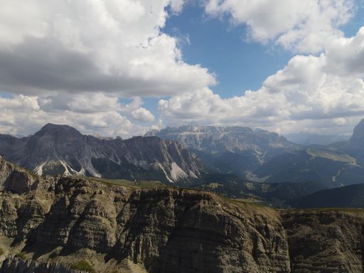 An aerial of Seceda Mountain with floating clouds above in the Alps of Italy