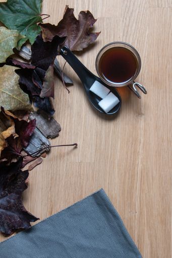 A top view of a cup of hot tea with sugar cubes on the wooden surface