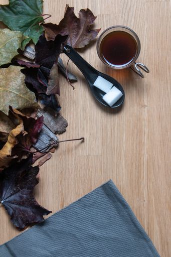A top view of a cup of hot tea with sugar cubes on the wooden surface