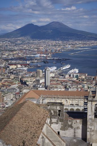 A vertical shot of the Mount Vesuvius surrounded by the sea and buildings in Naples, Italy