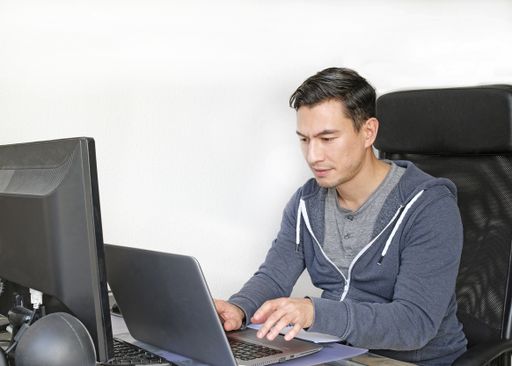 A young man in a casual outfit typing on his laptop and working from home