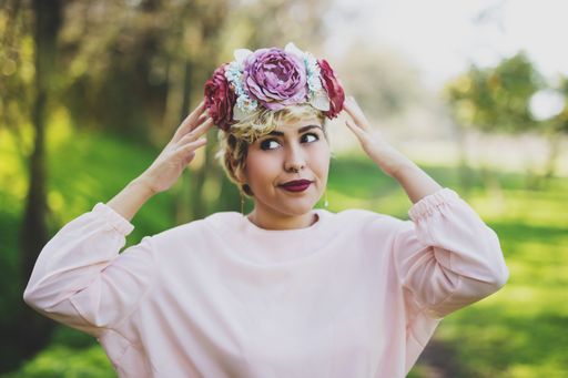 A portrait of a young female with a flower crown on her head in a park