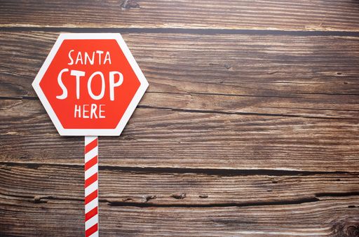 A red traffic sign saying "Santa stop here" on wooden background