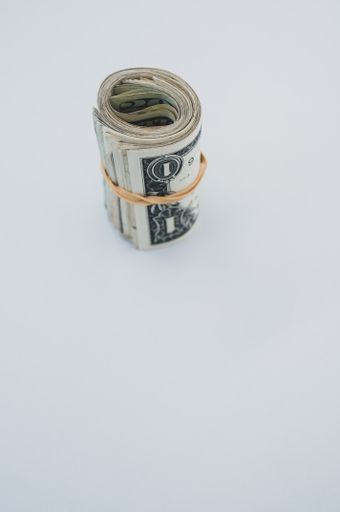 A vertical top view shot a bundle of rolled American banknotes isolated on a light blue background