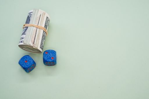 A bundle of rolled-up American banknotes and two dice isolated on a light blue background