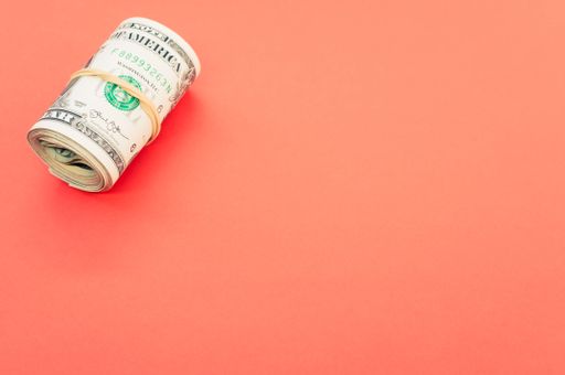 A high angle shot of rolled-up dollar bills on a red surface
