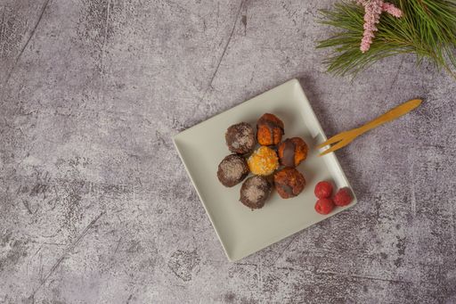 sweet truffles of different flavors on a white ceramic plate a brick wall in the background