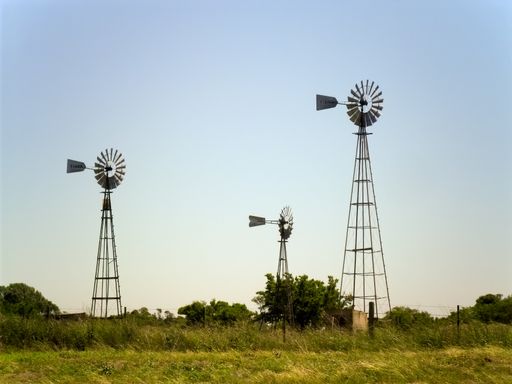 Three old windmills in a field under the sunlight in Buenos Aires Argentina