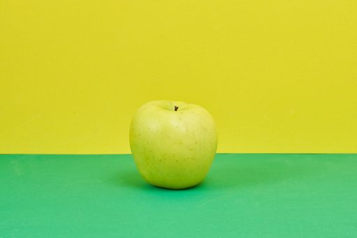 A closeup shot of an apple on a green and yellow background