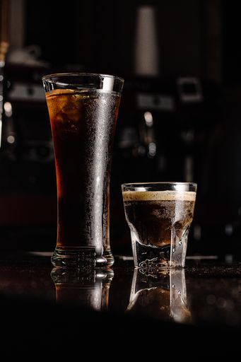 A vertical shot of glasses of liquor and coffee with reflections