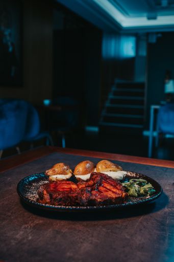 A vertical shot of delicious grilled meat, grilled potatoes with cheese, and basil on the plate
