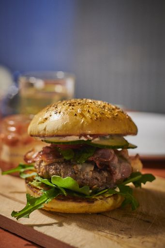 A fresh burger on a wooden cutting board in the kitchen with a  blurry background