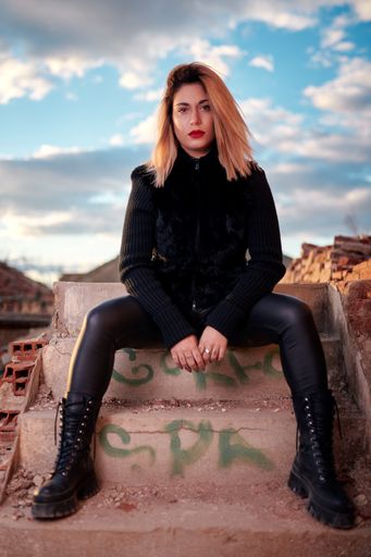 A vertical shot of a Caucasian attractive woman wearing black clothes with a red lipstick looking confident