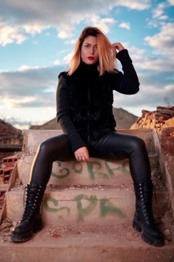 A vertical shot of a Caucasian attractive woman wearing black clothes with a red lipstick looking confident