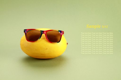 A juicy lemon with colorful sunglasses on a green background with space for text