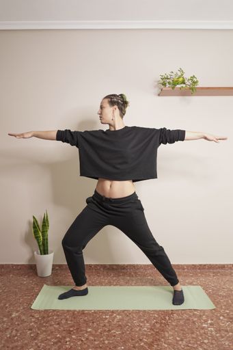 A young female wearing sportswear and doing yoga in her room