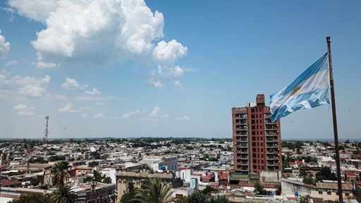A closeup of Argentinian flag waving in the wind against a blue sky with Victoria city in the background, Entre Rios, Argentina