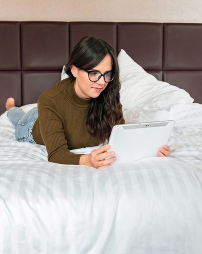 A cheerful young Caucasian woman wearing glasses video chatting with a tablet at home