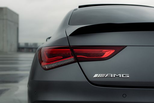 A closeup of the tail lights of a matte grey Mercedes AMG parked outdoors