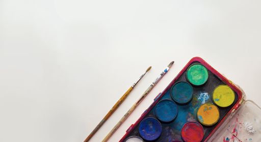 A top view of paintbrushes and a watercolor palette on a white background
