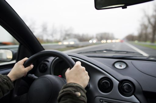 A shallow focus shot of female hands holding the steering wheel of a car