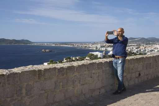 A Caucasian tourist man taking photoes with his mobile phone