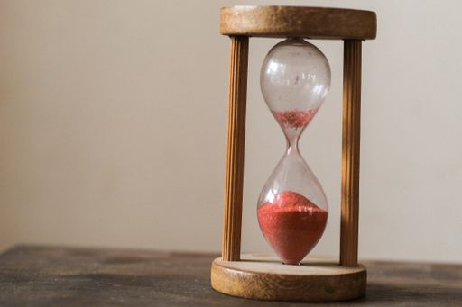 A closeup shot of a wooden hourglass with red sand