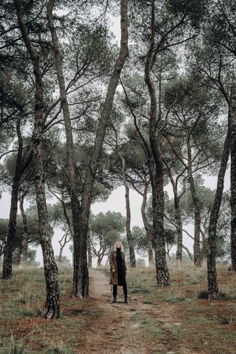 A vertical shot of a young caucasian female posing at camera in the forest