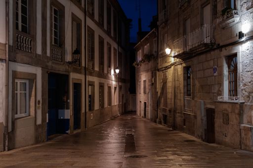 A wet narrow street among buildings at night