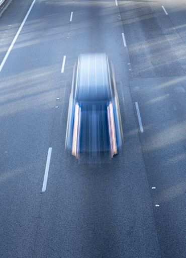 A vertical high angle shot of a car going very fast on the highway