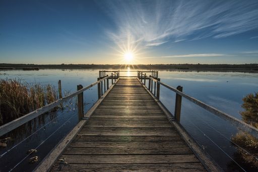 A beautiful wooden pier by the calm ocean with the beautiful sunset over the horizon
