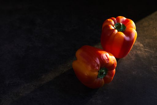 A high angle shot of two red peppers on a black surface