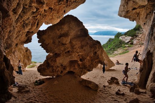The athletic international tourists climbing on a cave overlooking the sea