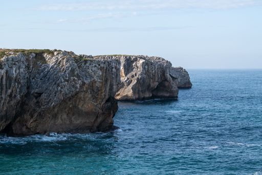 A scenic view of a rocky coastline against a blue sea on a sunny day