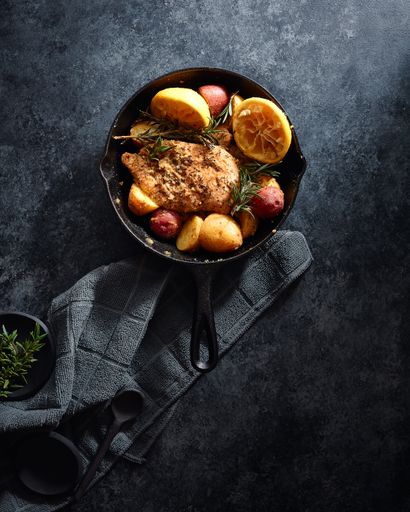 A vertical high angle shot of meat and vegetables in a black pot on a black surface