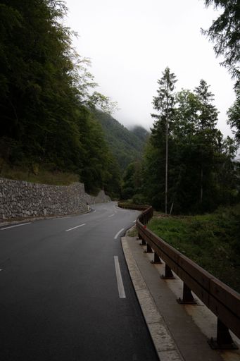 A vertical shot of a winding road in Italy with mountains and trees