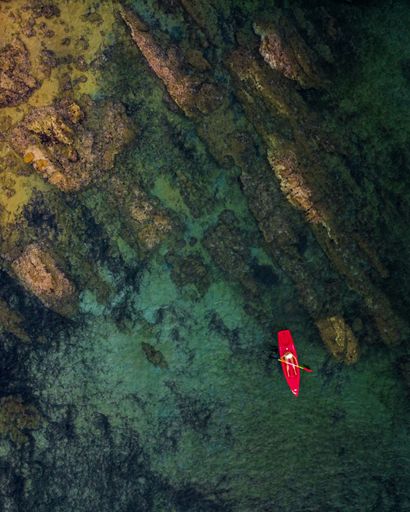 A vertical drone view of a kayaker in the sea near Skiathos island, Greece