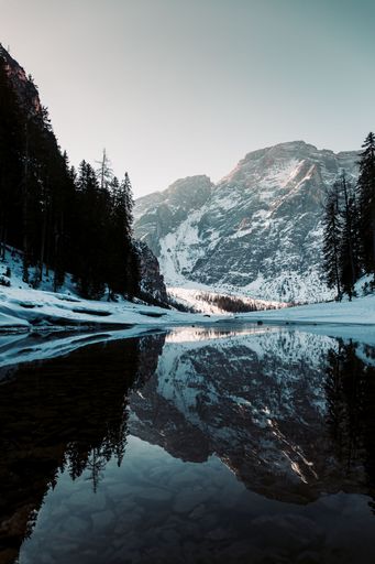 A vertical shot of Lake Braies reflecting the snowy Dolomites mountains in South Tyrol, Italy
