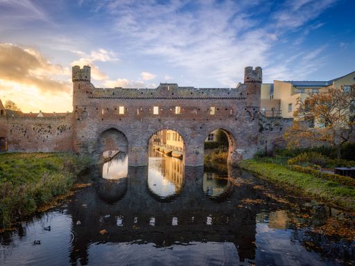 The Watergate of Zutphen with visible reflection on water in  Gelderland, the Netherlands at sunset