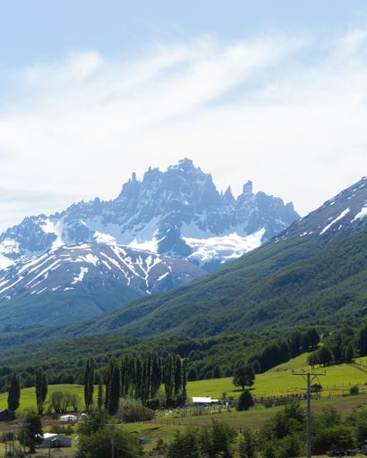 A vertical shot of a beautiful landscape with tree-covered hills and high mountains