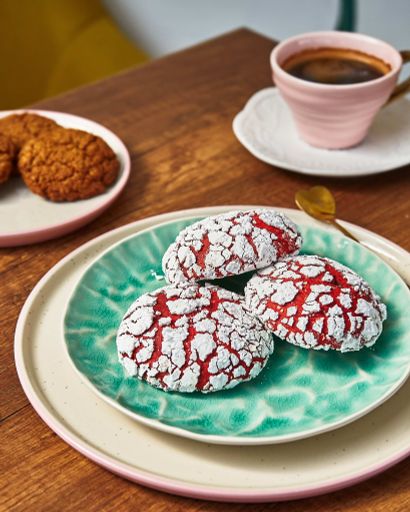 A plate of red velvet cookies accompanied with a cup of coffee