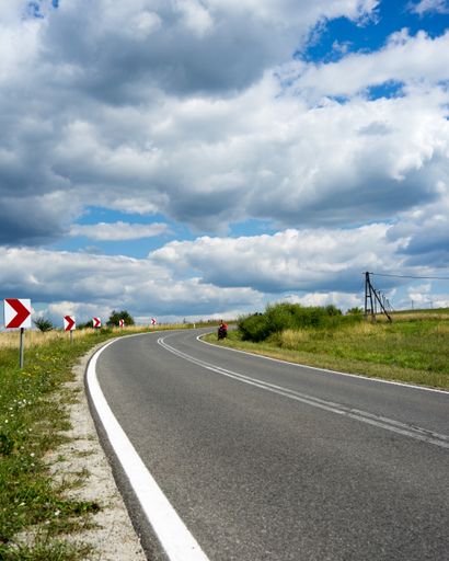 A highway surrounded by street signs near a grassy field under the cloudy sky
