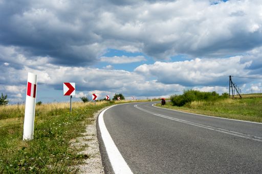 A highway surrounded by street signs near a grassy field under the cloudy sky