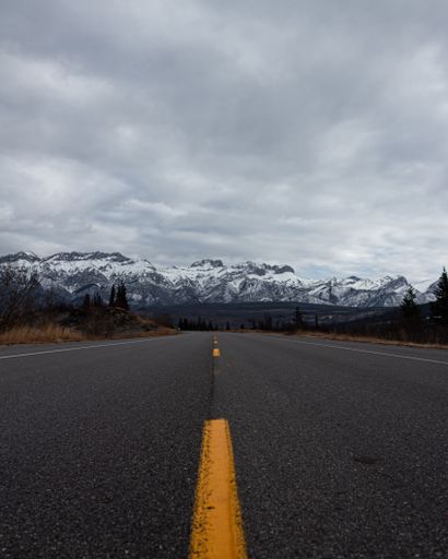 A vertical shot of a road under the cloudy sky