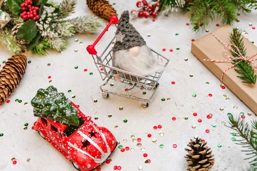 A closeup of a surface filled with Christmas toys, pine cones and leaves, present, and a mini shopping cart